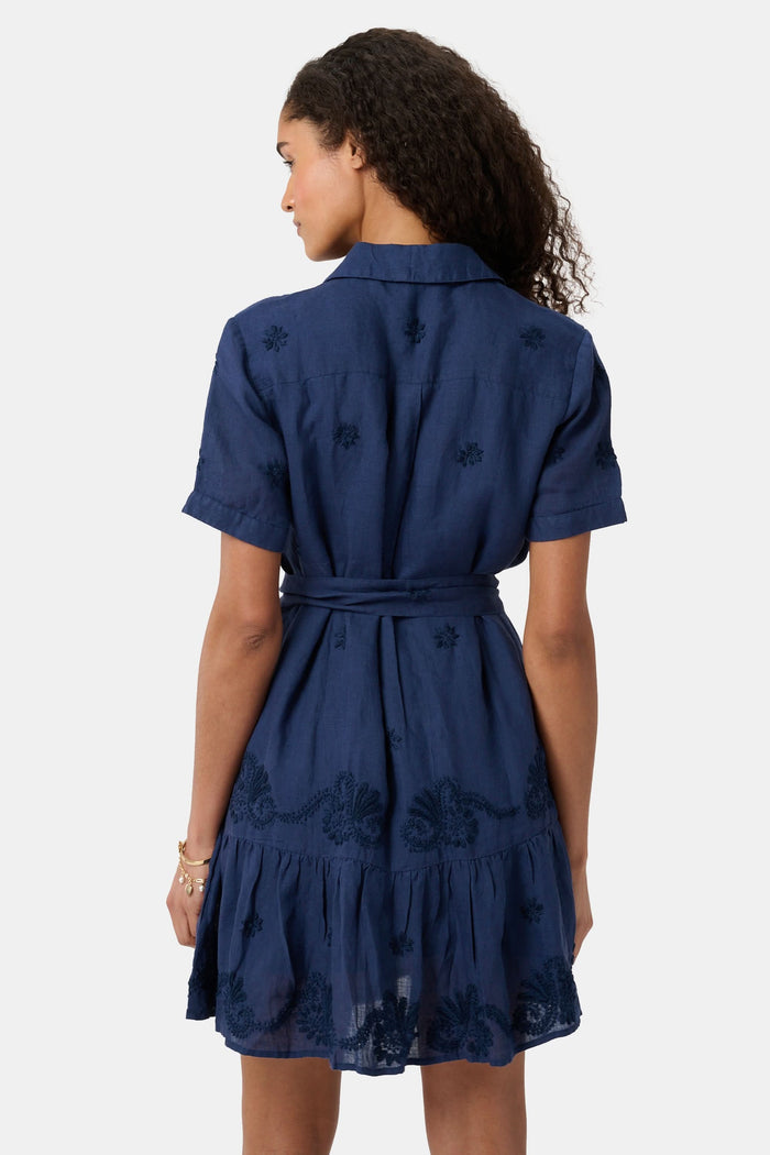 A woman models the Roller Rabbit Vanna Embroidery Margaret Dress—a short-sleeve navy linen shirtdress with a belted waist—standing against a plain light background.