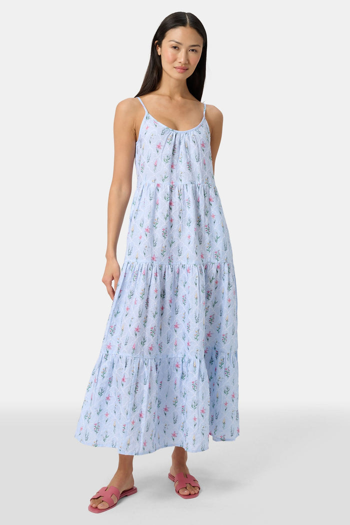 A woman with long hair stands facing forward, wearing the Roller Rabbit Wildflower Jemina Dakota Dress in sky blue and pink sandals.