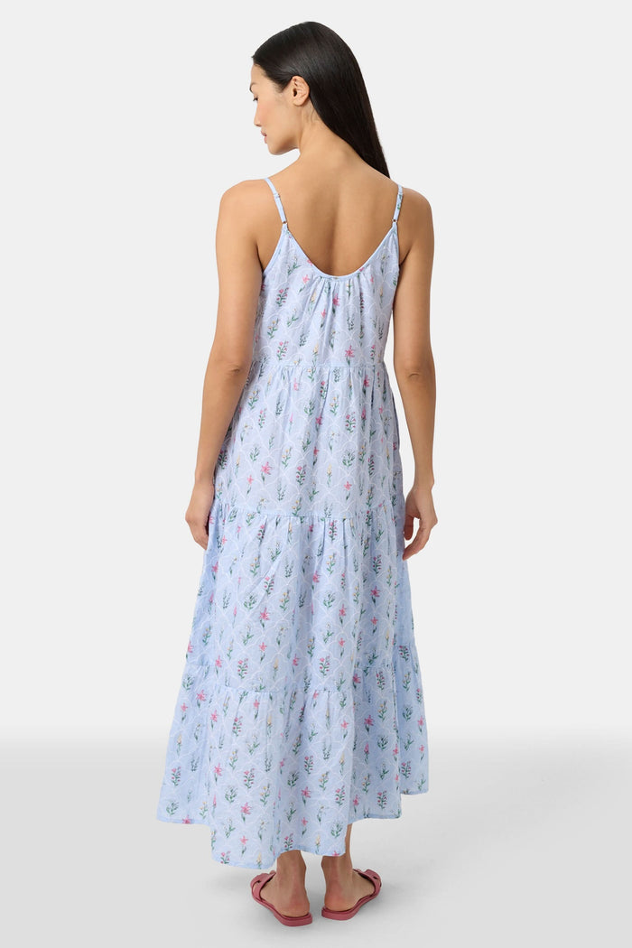 A woman with long hair stands facing forward, wearing the Roller Rabbit Wildflower Jemina Dakota Dress in sky blue and pink sandals.